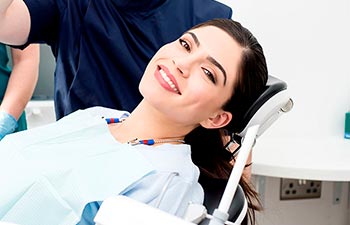 Satisfied relaxed young woman in a dental chair after fluoride treatment.